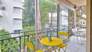 Een balkon met gele stoelen, een tafeltje en een lantaarn.