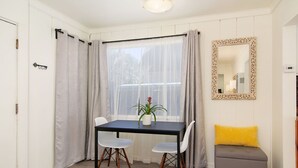 A dining area with a table, chairs, a potted plant, a bench, and a mirror. - Bay View Cottage | Patio, W/D, Parking, Location! (San Diego)