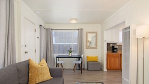 A compact living space with a sofa, a coffee table, a dining table with chairs, a kitchen area, and a small seating area. - Bay View Cottage | Patio, W/D, Parking, Location! (San Diego)