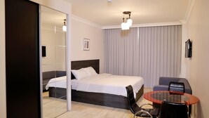 A modern hotel room with a large bed, a glass table, a sofa, and a mirror. - Abu Alsoud Hotel (Amman)