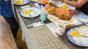 A group of people dining at a table with various dishes, including bread and vegetables. - Casa Laureles (Filandia)