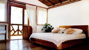A wooden-framed bedroom with a bed, white curtains, and a potted plant. - Casa Laureles (Filandia)