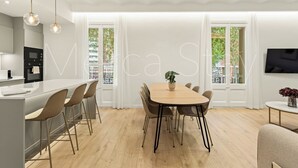 Eine moderne Küche mit Einbauofen und Essbereich mit Holztisch und Korbstühlen.