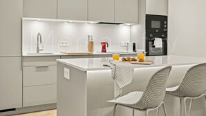 Eine moderne Küche mit einer zentralen Kochinsel, weißen Schränken und einem schwarzen Backofen.