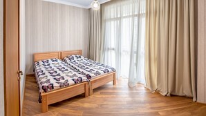 Een slaapkamer met een houten bed, een hanglamp en dunne gordijnen.