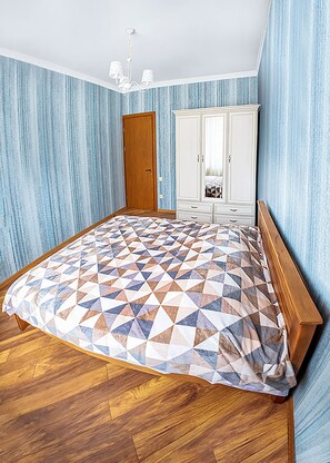 A bedroom with a wooden bed, a white wardrobe, and blue-striped wallpaper. - HB apartments Vazha Pshavela (Tbilisi)