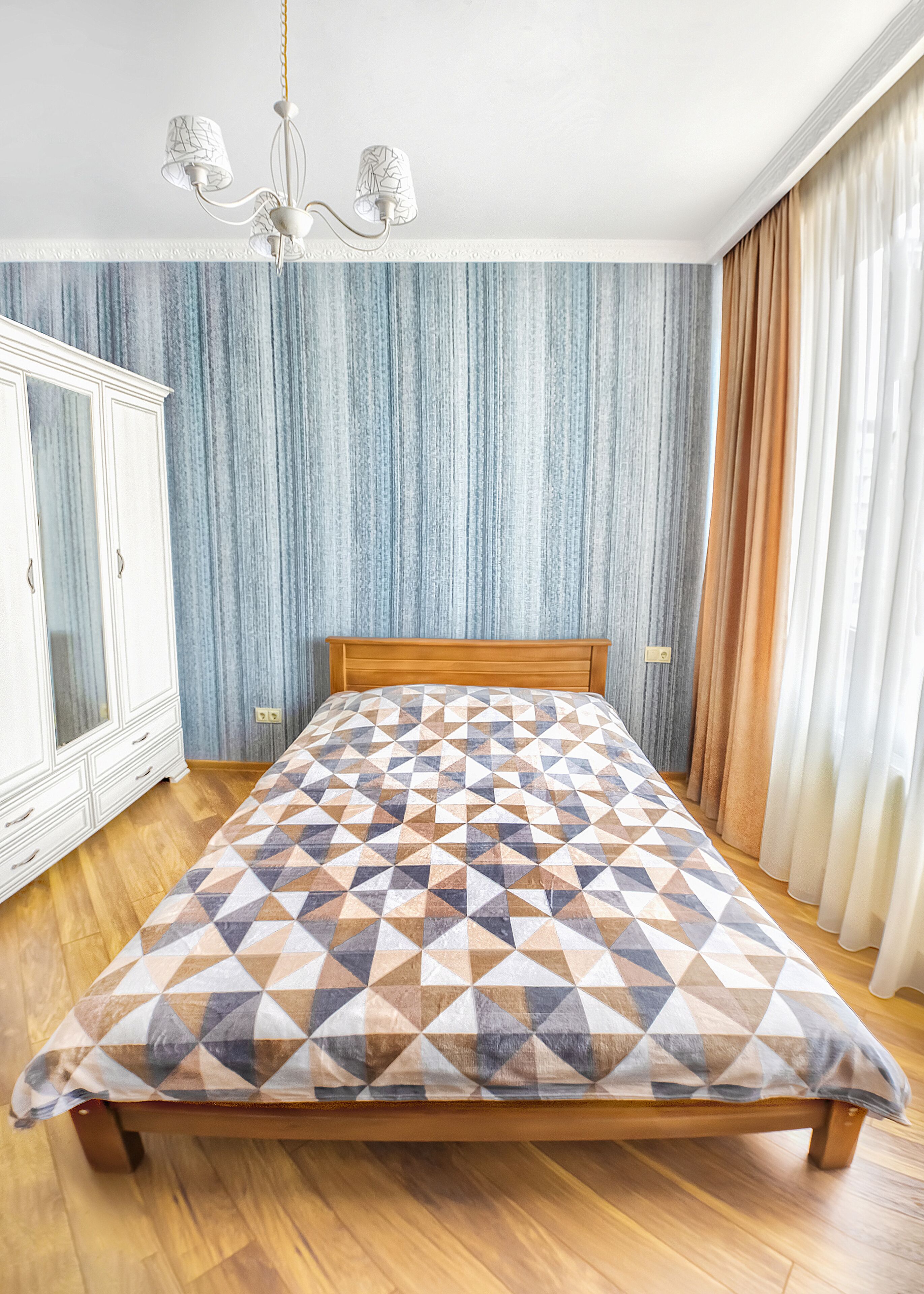Un dormitorio con una cama de madera, un armario blanco y una pared con diseño.