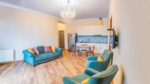 Een moderne woonkamer met een bank, twee fauteuils, een eettafel en een keuken.
