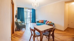 Een ruime woonkamer met een eettafel en stoelen, een zithoek en een kroonluchter.