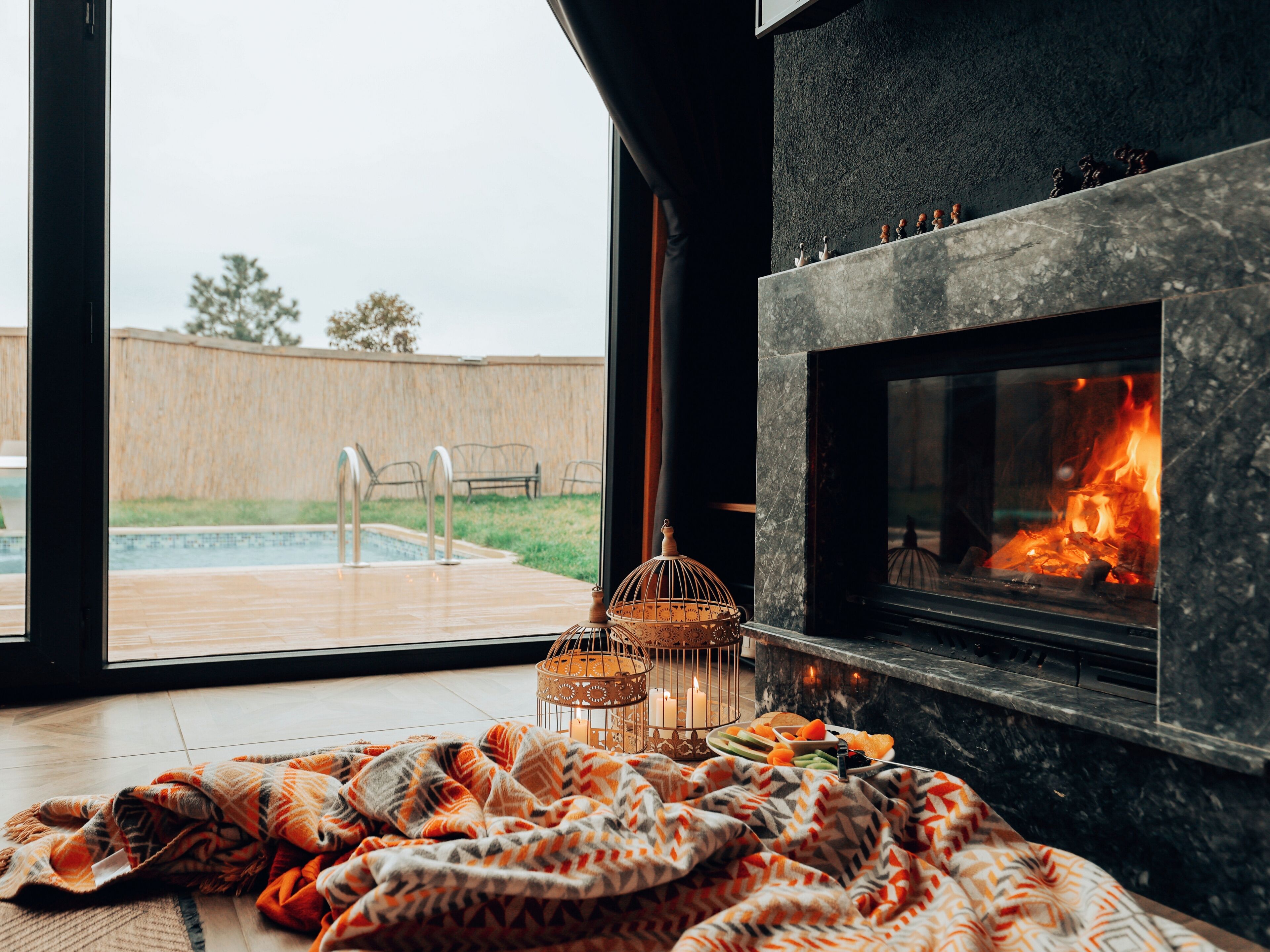A cozy room with a fireplace, a pool view, and a wicker lantern.