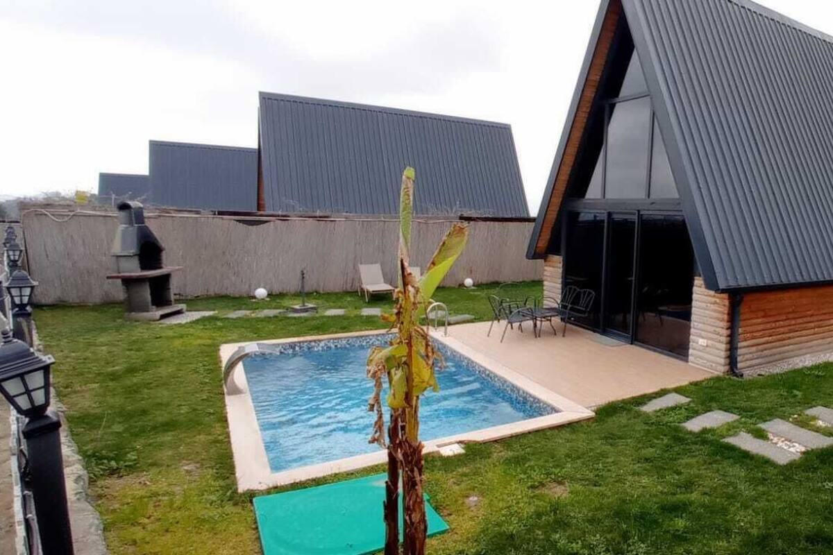 A modern house with a swimming pool, a patio, and a wooden deck.