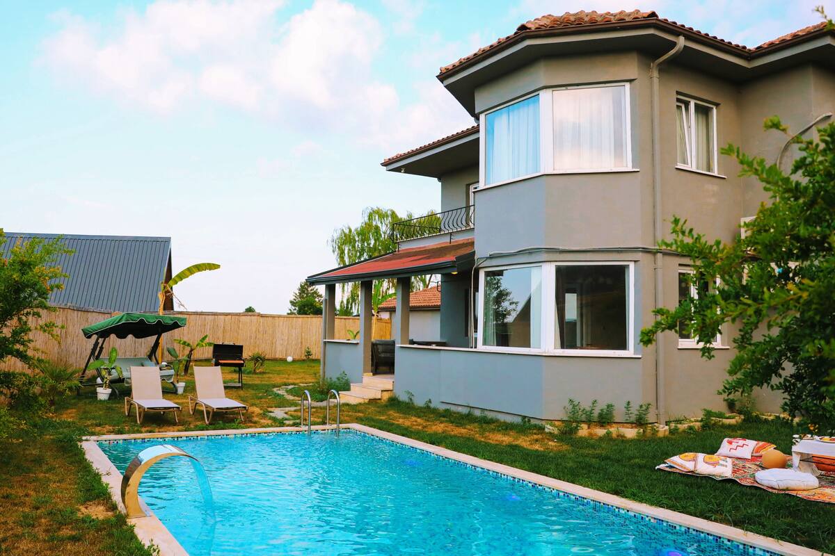 A two-story house with a swimming pool, a covered patio, and a fenced backyard.