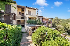 A traditional Mediterranean-style building with stone walls, multiple balconies, and lush greenery.