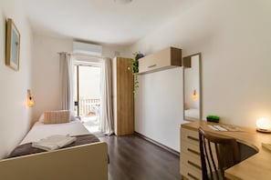 Une chambre à coucher comprenant un lit, un bureau, une chaise, une commode, un miroir et une plante en pot.