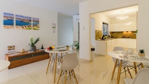 A modern kitchen with white cabinets and a dining area with a round table and chairs. - SwieqiStay room2 private bath - Paceville (Swieqi)