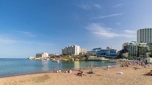 A beach with people sunbathing and swimming, surrounded by buildings and a clear sky. - SwieqiStay room2 private bath - Paceville (Swieqi)