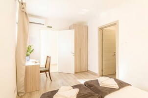 A hotel room with a bed, a desk, a chair, and a wardrobe.