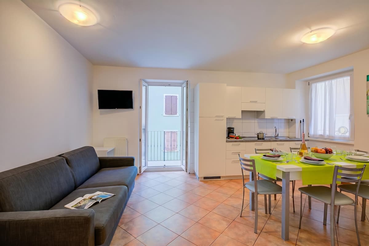 Un appartement moderne comprenant un espace de vie, une kitchenette, un coin repas et un balcon.