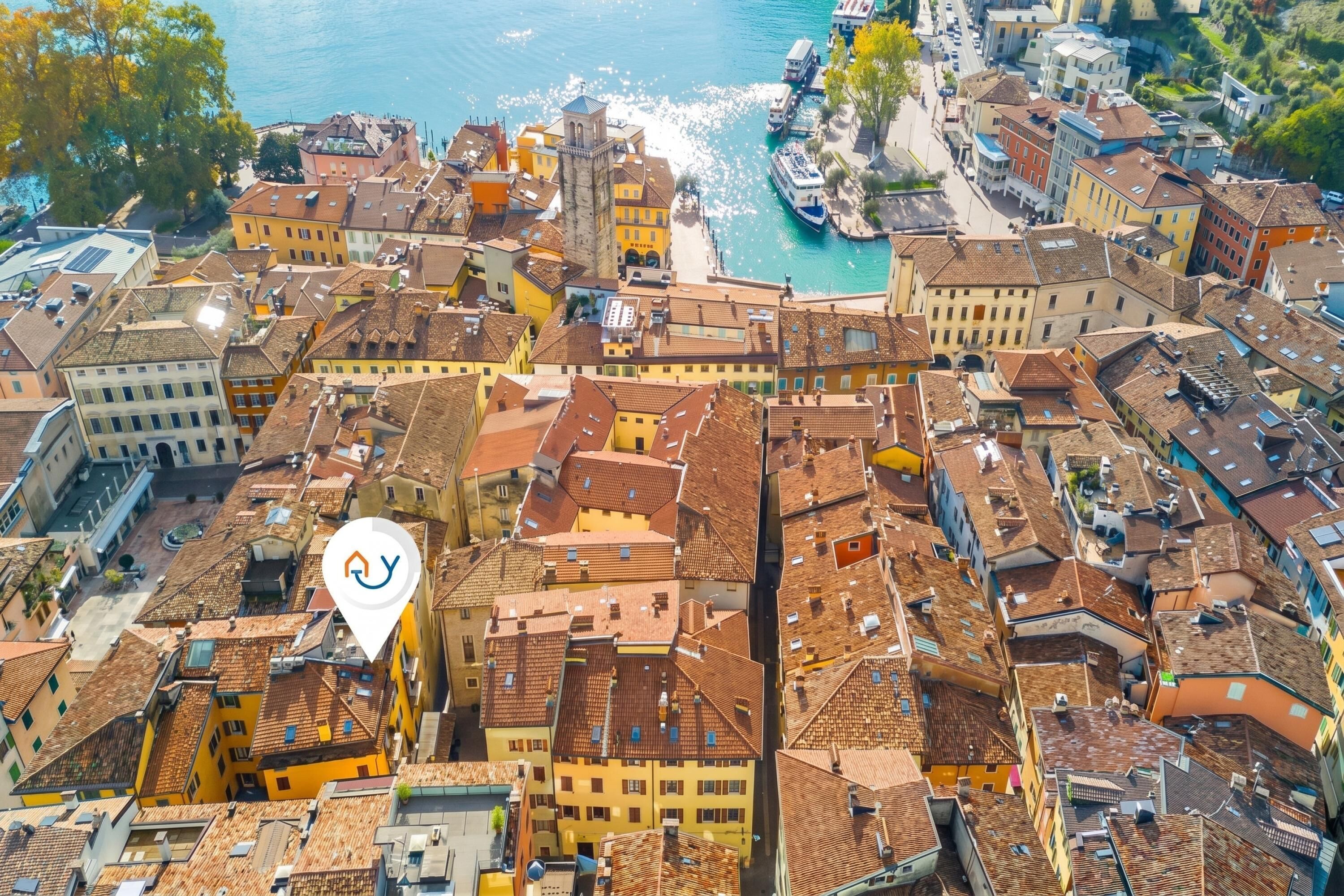 An aerial view of a densely packed urban area with historic buildings, narrow streets, and a body of water in the background.