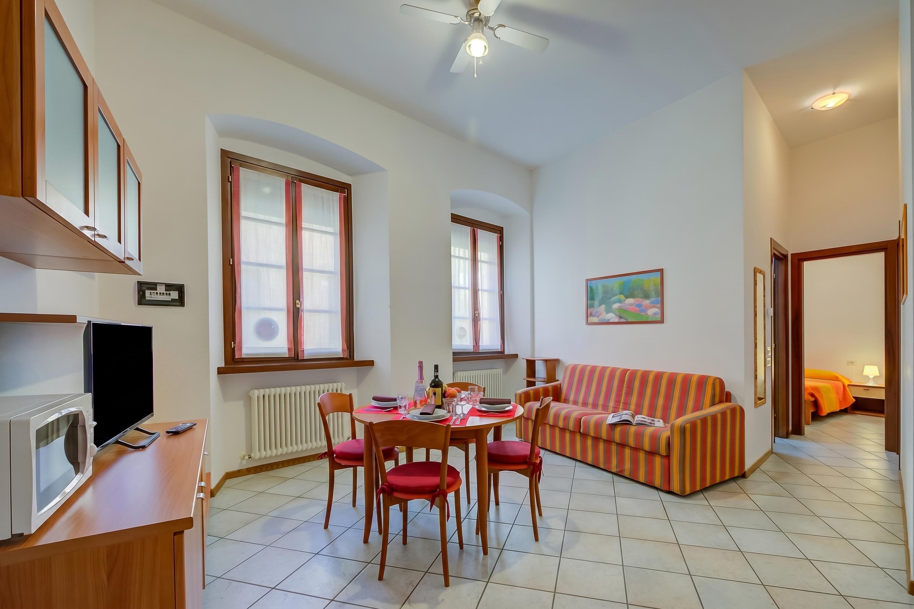 Un salon comprenant une table à manger, des chaises, un canapé, un téléviseur et un ventilateur de plafond.
