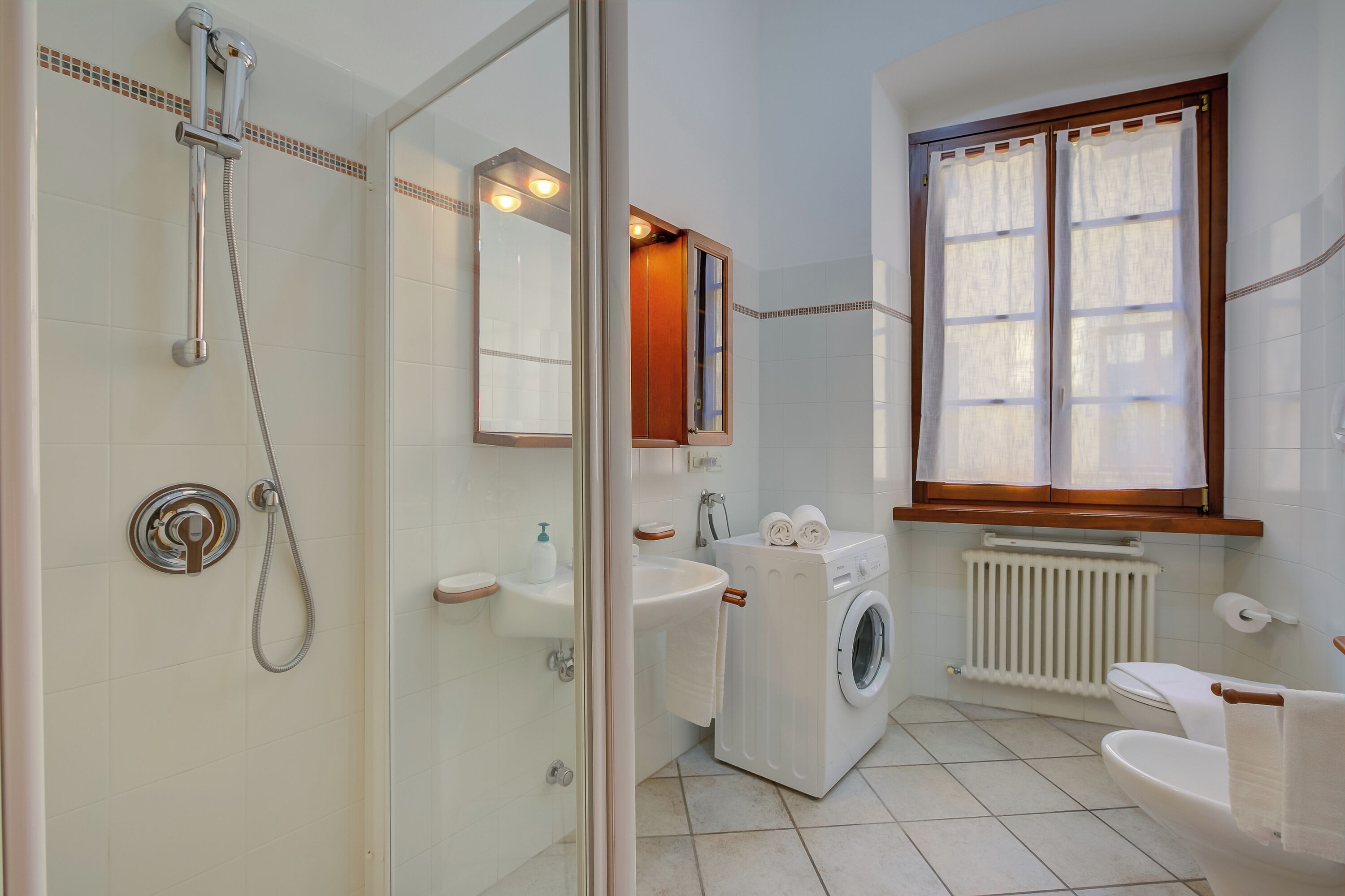 A bathroom with a shower, sink, toilet, and a washing machine.