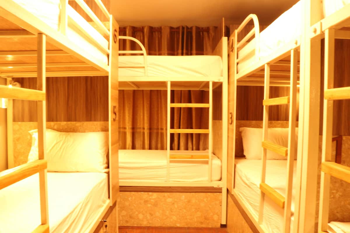 Ein Zimmer mit Etagenbetten, Holzgeländern und Vorhängen.