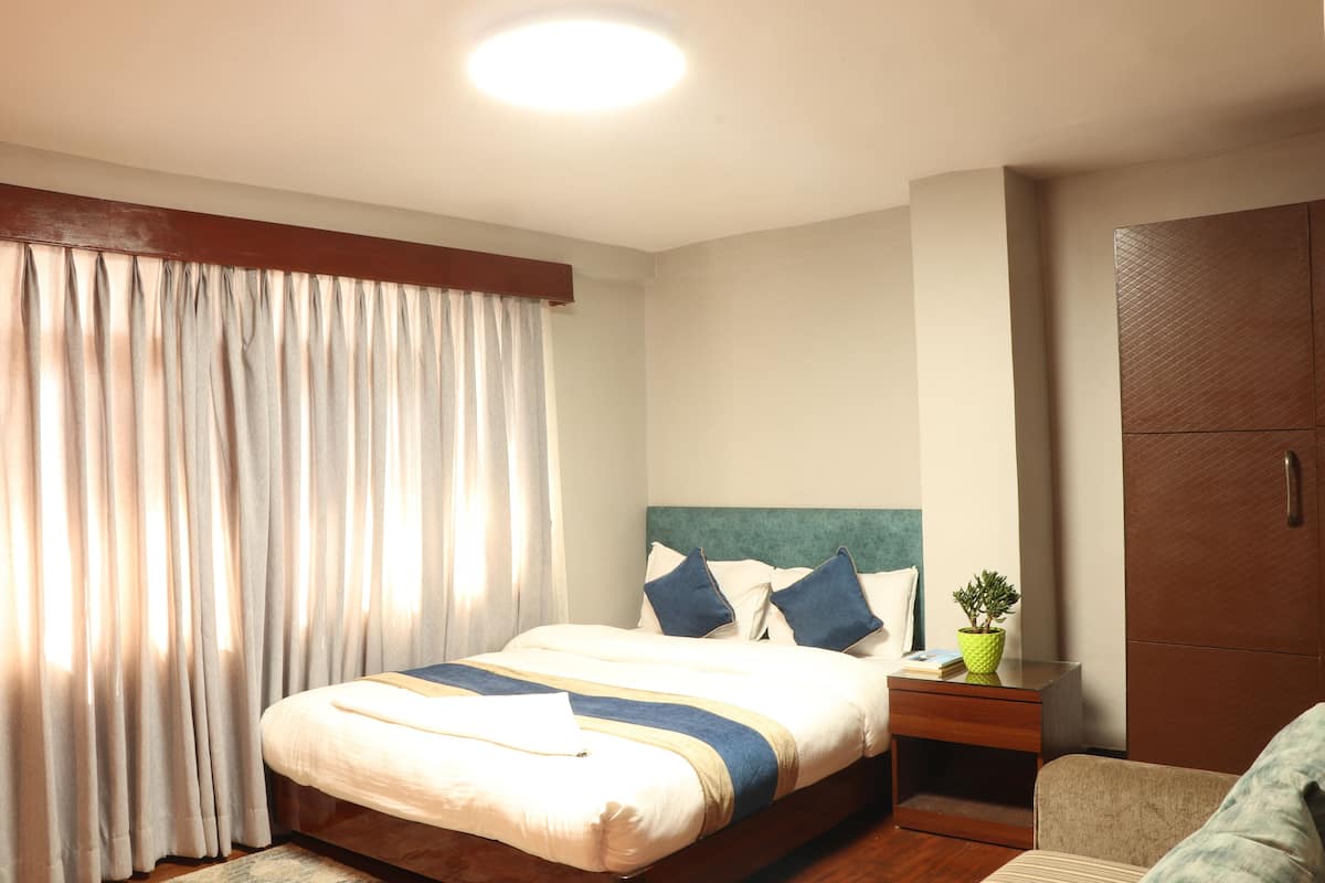 Ein Hotelzimmer mit Bett, Nachttisch, Topfpflanze und Kleiderschrank.
