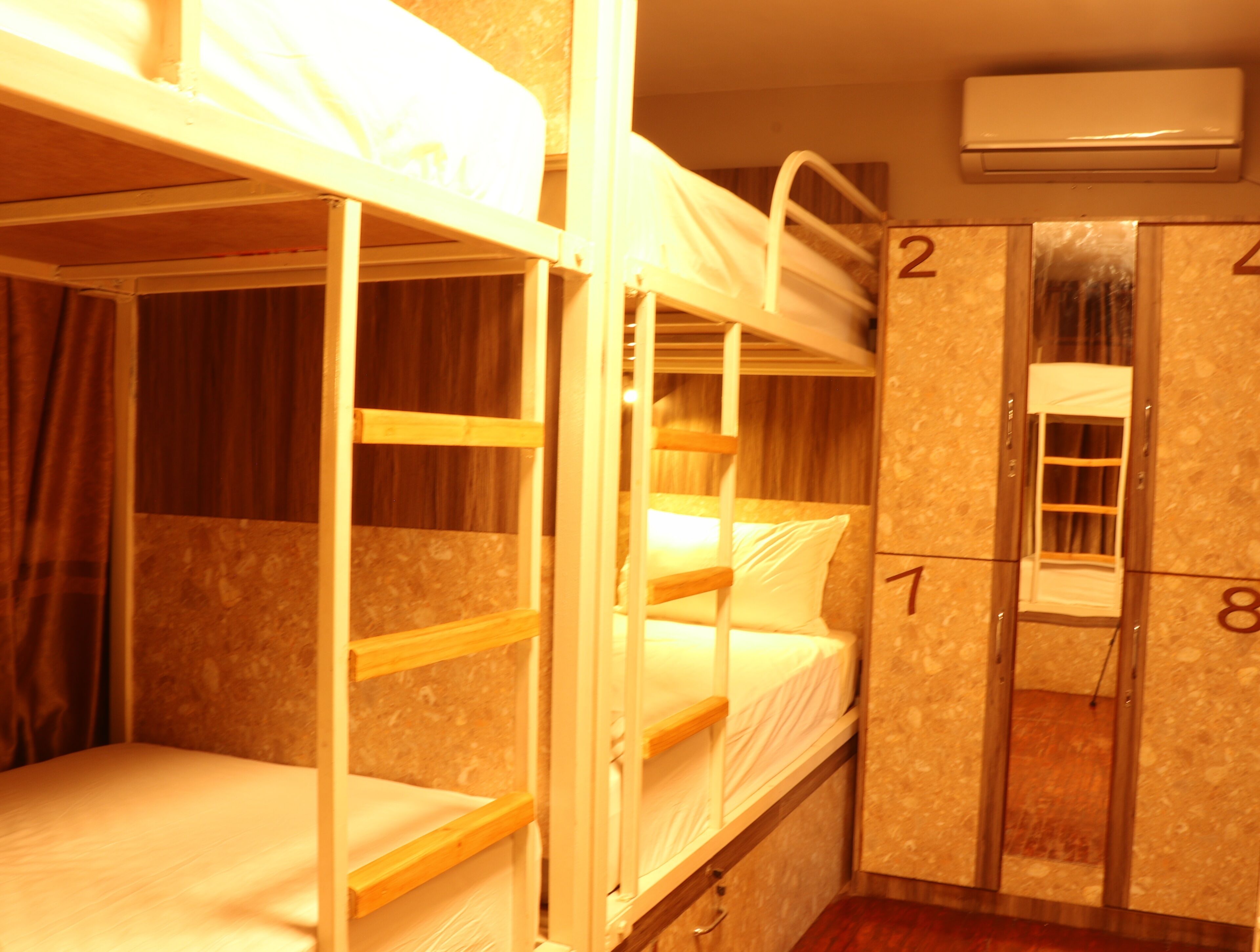 A bunk bed room with a wooden bunk bed, a single bed, and a wardrobe with numbered doors.