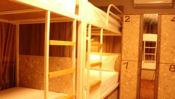 A bunk bed room with a wooden bunk bed, a single bed, and a wardrobe with numbered doors.