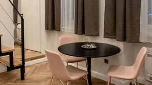 Un comedor con una mesa redonda, dos sillas y una ventana con cortinas.