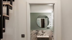 Un dormitorio compacto con literas y un baño pequeño con lavamanos y espejo.