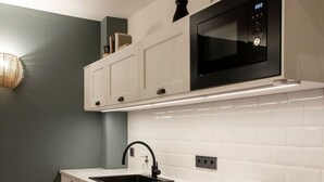 Una cocina moderna con armarios blancos, un microondas negro, un lavamanos y un horno empotrado.