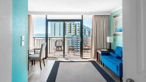 Hotellihuone, jossa on parveke, sohva, tuoli ja työpöytä.