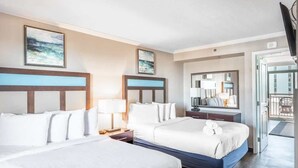 Hotellihuone, jossa on kaksi sänkyä, suuri peili, parveke ja taideteoksia seinillä.