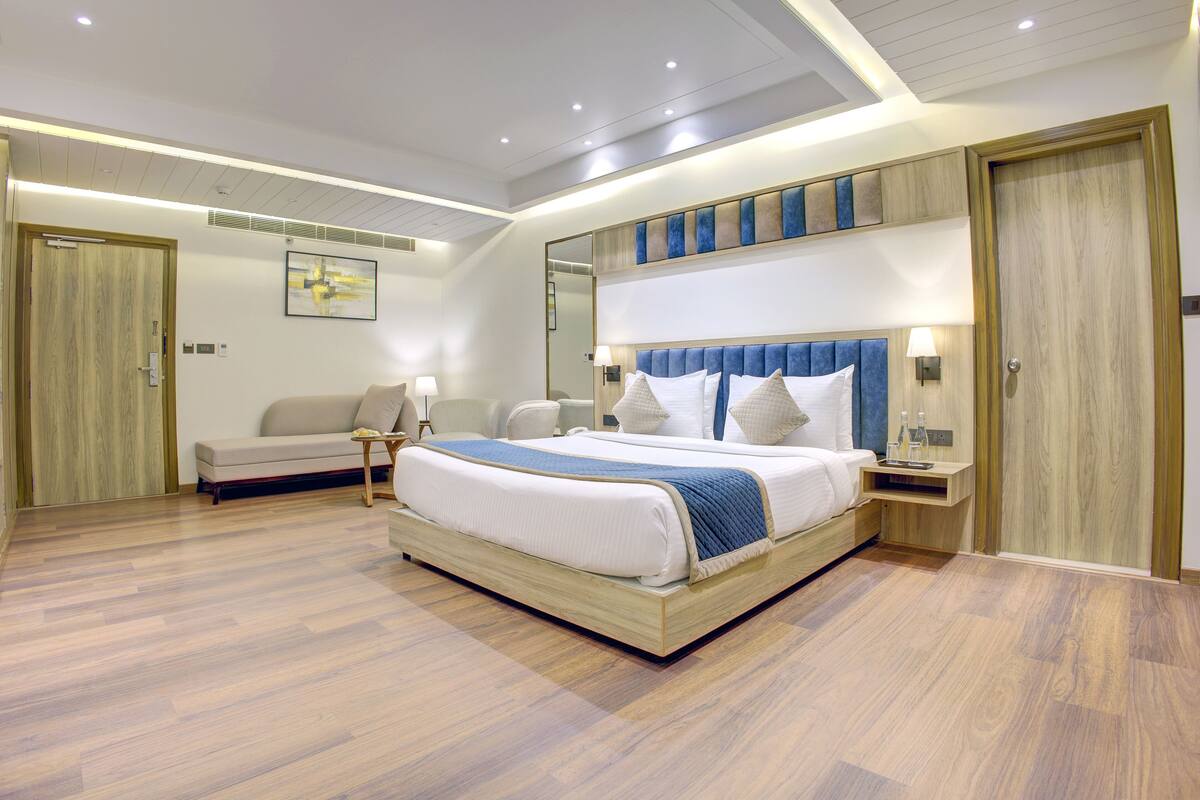 Une chambre d’hôtel moderne, dotée d’un grand lit, d’un canapé, d’un bureau et d’un miroir.