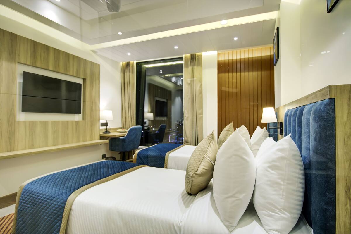 Une chambre d’hôtel avec deux lits, une télévision, un bureau et une chaise.