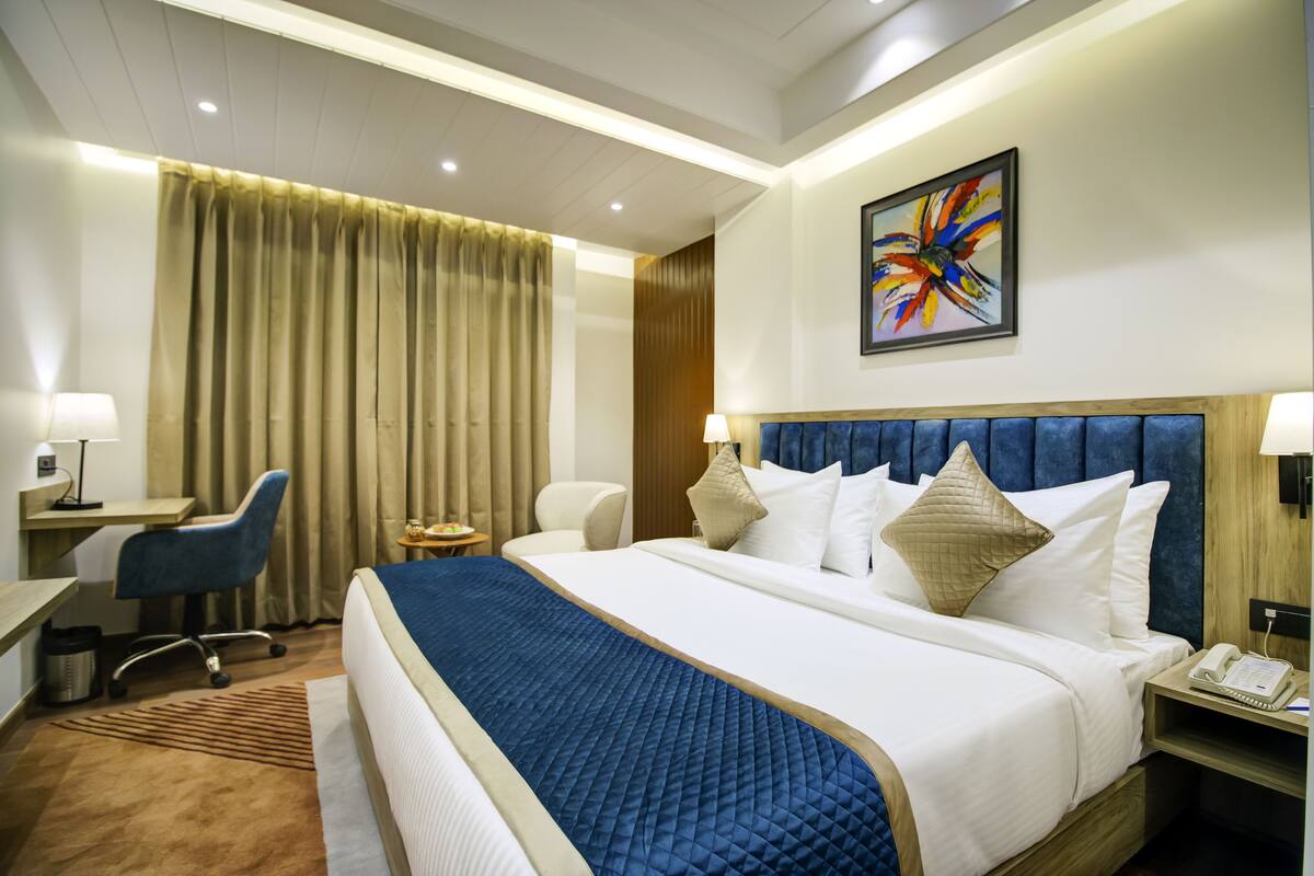 Une chambre d’hôtel avec un grand lit, un bureau, une chaise et une table de chevet avec un téléphone.