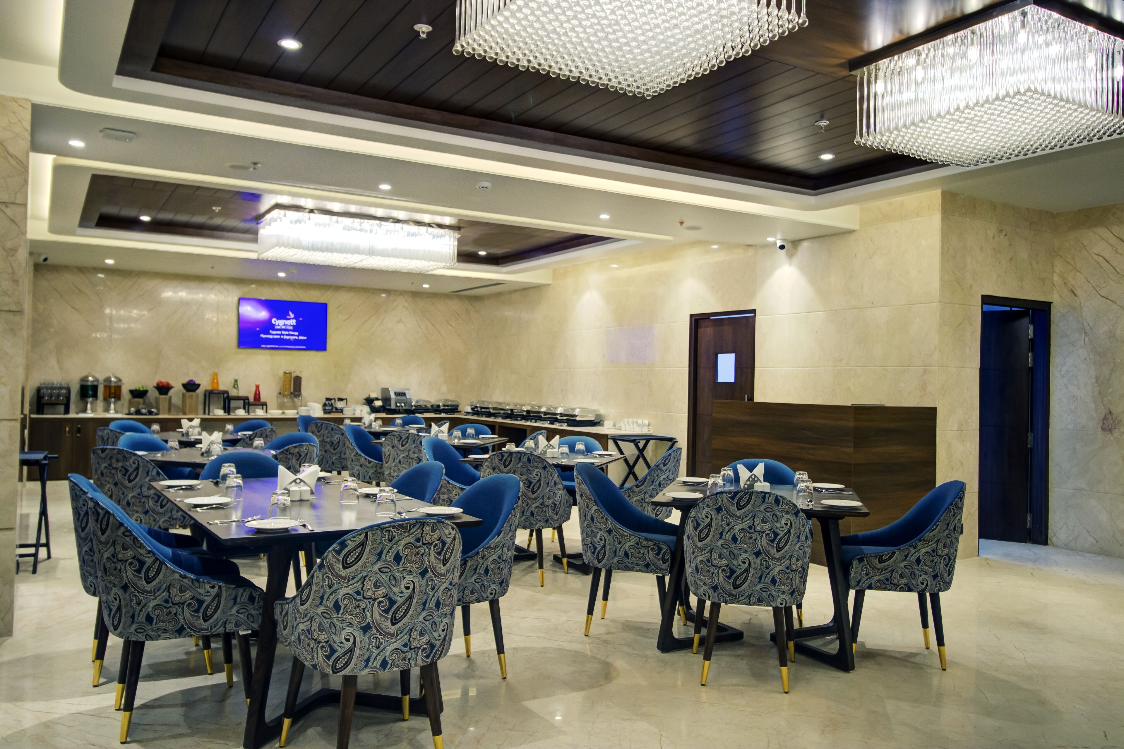 A conference room with a large screen, multiple tables, and chairs.