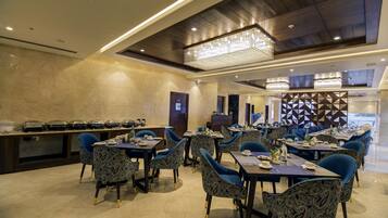 A modern dining area with patterned chairs, tables set with plates and cutlery, and a decorative wall with geometric patterns.