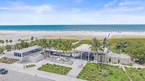 A beachside hotel with a pool area, palm trees, and a view of the ocean.