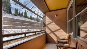 A balcony with a wooden bench, a view of a snowy landscape, and a clear sky. - Premium Unit 1307 - 1 Bedroom - Zephyr Mountain 1 Condo (Winter Park)