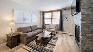 A modern living room with a sofa, coffee table, side table, and a fireplace. - Premium Unit 1307 - 1 Bedroom - Zephyr Mountain 1 Condo (Winter Park)