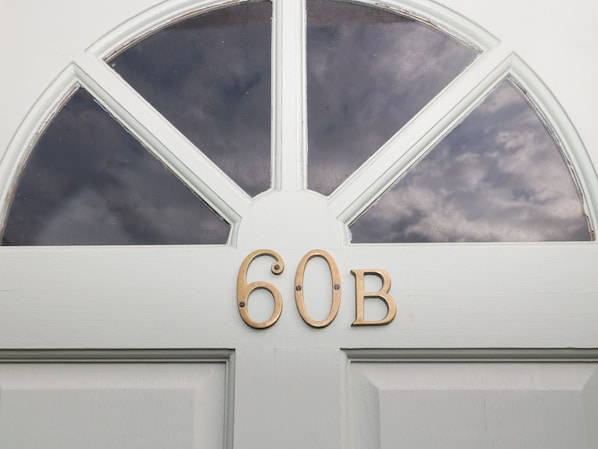 Una puerta blanca con un amplio ventanal arqueado y el número "60B" en letras de bronce.