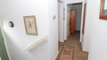 A hallway with white walls, a wooden door, and a patterned carpet.
