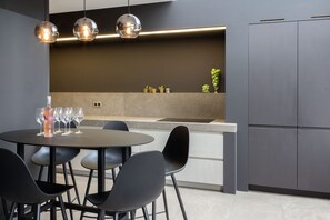 A modern kitchen with a round dining table, black chairs, and pendant lighting. - TUSS (Kortrijk)