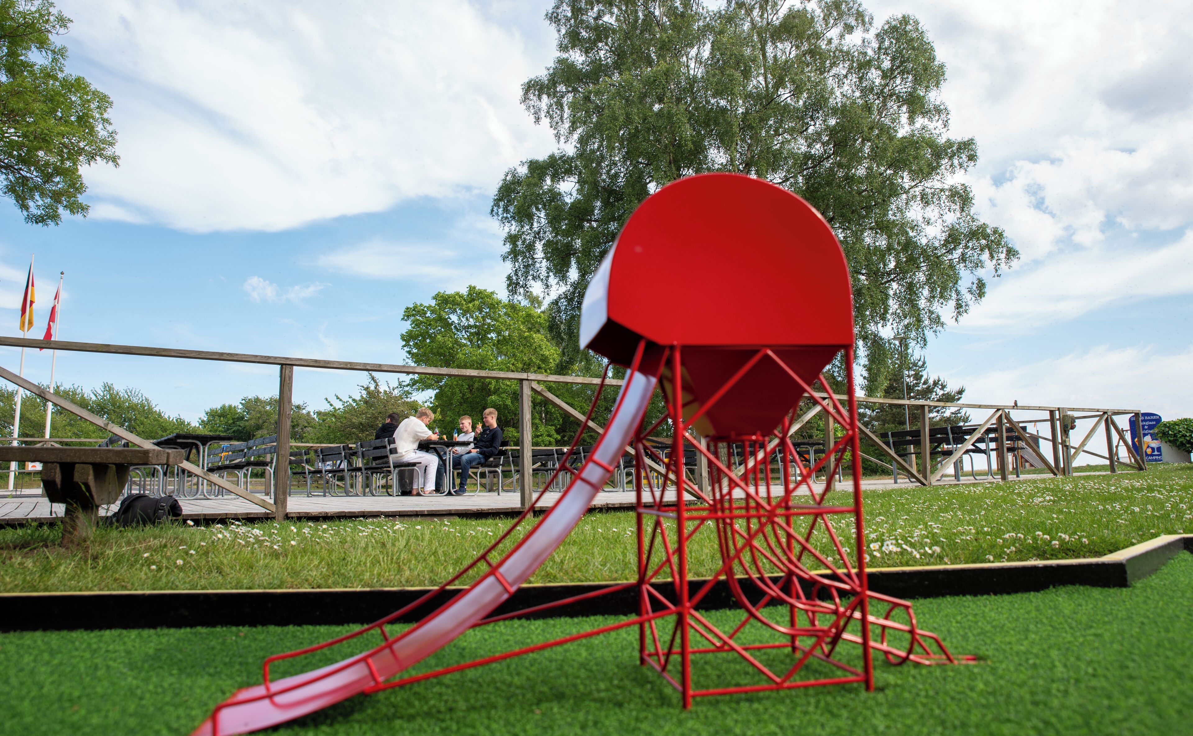 A playground with a red slide and a large red structure.