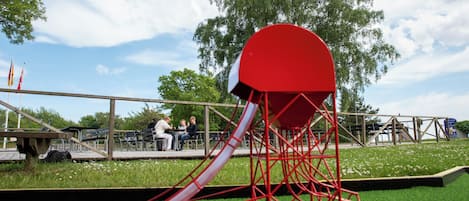 A playground with a red slide and a large red structure.