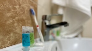 A bathroom sink with two toothbrush tubes labeled "HOTEL SHOWER" and a toothbrush.