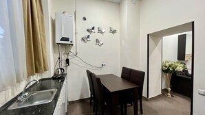Een kleine keuken met een spoelbak, fornuis en een eethoek.