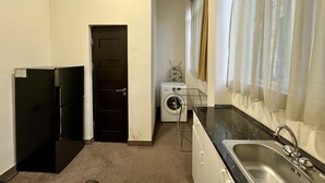 Een kleine keuken met een koelkast, wasmachine en spoelbak.
